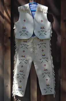 A traditional Native American Boys Vest and Breaches with colorful bead embroidery hanging on a wooden background.