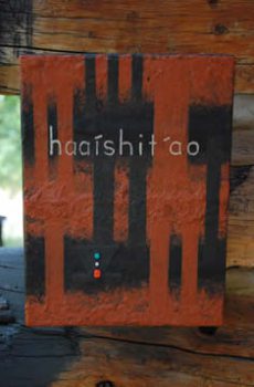 Abstract black, orange, and red canvas painting with the word "haaishit'ao" on a wooden background.