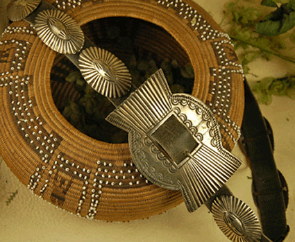 Circular African necklace with intricate beadwork and a large, Ingot Silver Buckle with 9 Conchos, displayed on a textured surface.