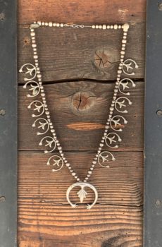 A wooden wall with a necklace hanging on it.