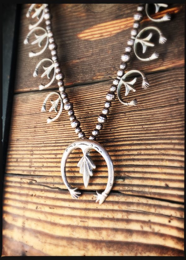 A necklace with an arrow and feathers on it.