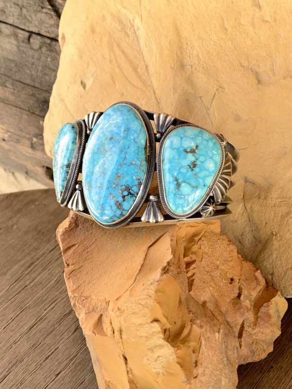 A turquoise bracelet is sitting on top of a rock.
