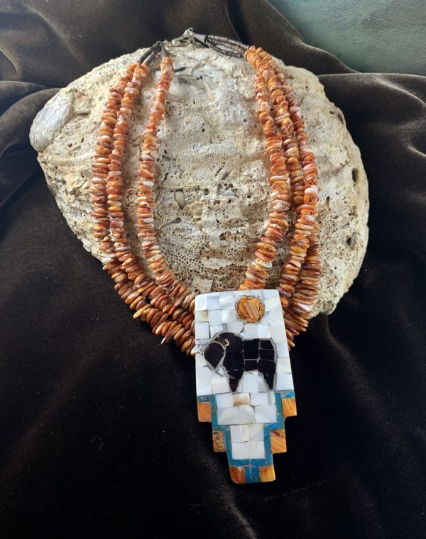 A necklace with an animal on it and two strands of beads.
