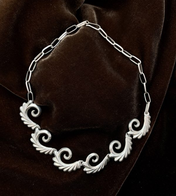A necklace with silver curls on it.