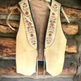 A vest hanging on the wall of a log cabin.