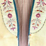 A close up of the front of an embroidered dress.