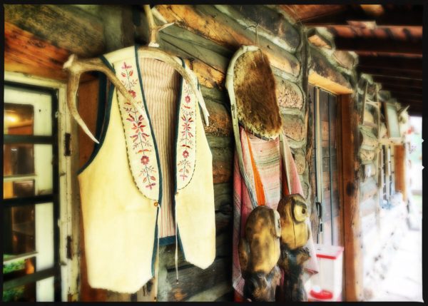 A bunch of native american clothing hanging on the wall.