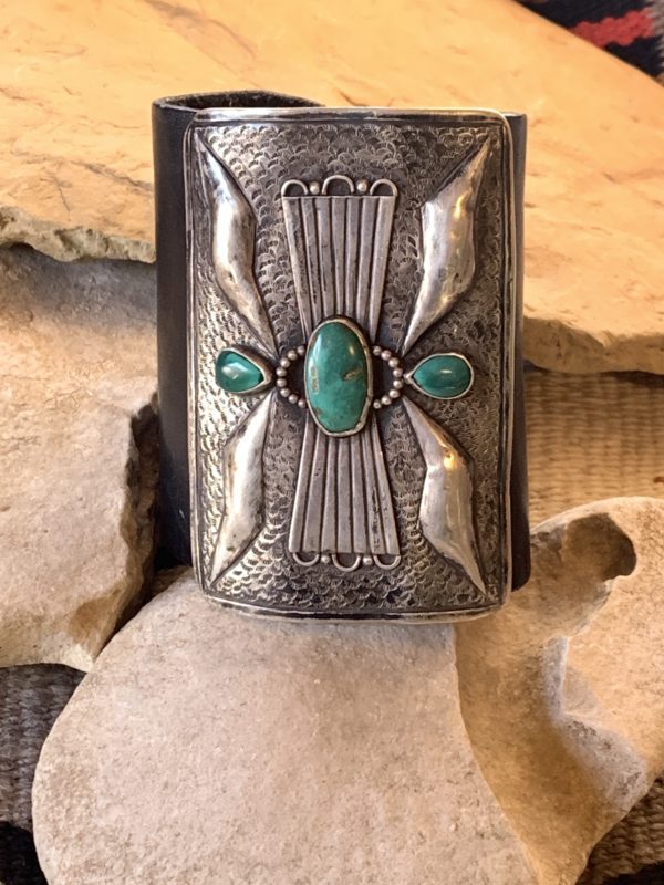 A silver and turquoise bracelet sitting on top of rocks.