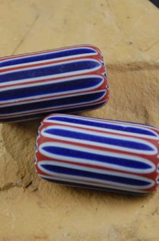 Two red, white and blue striped beads sitting on a table.