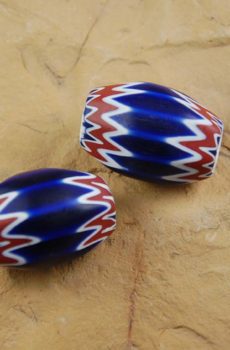 Two blue, white and red beads sitting on a table.