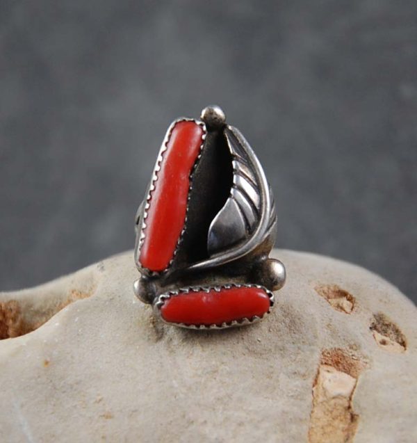 A silver ring with red stones on top of a rock.
