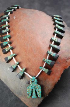 A necklace made of wood and turquoise is displayed.