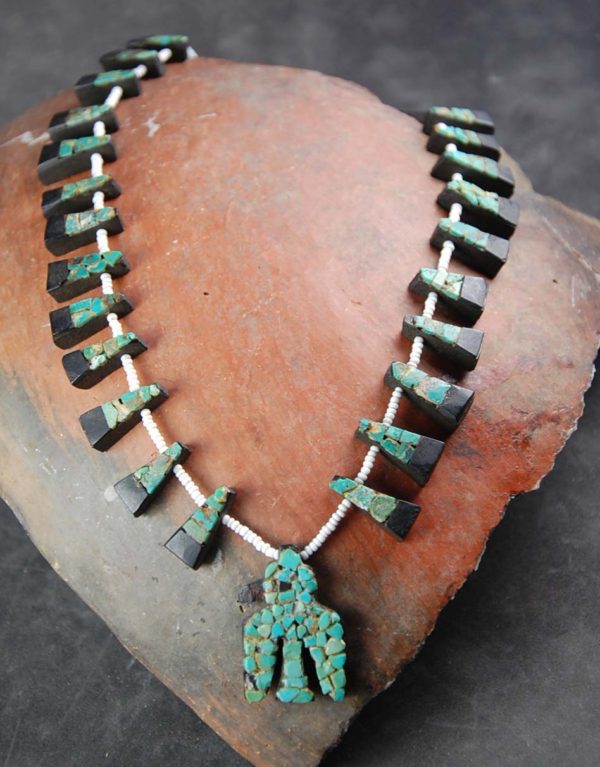 A necklace made of wood and turquoise is displayed.