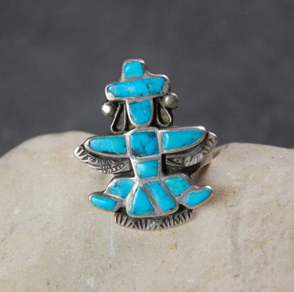 A turquoise inlay ring sitting on top of a rock.