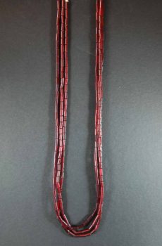 A pair of red beads hanging on a gray wall.