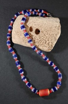 A necklace of blue and red beads is on the ground.