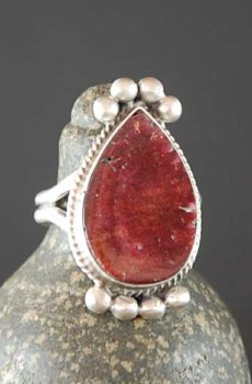 A red stone ring sitting on top of a silver ring.