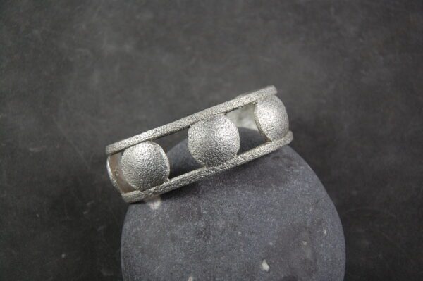 A silver ring with three balls on it.