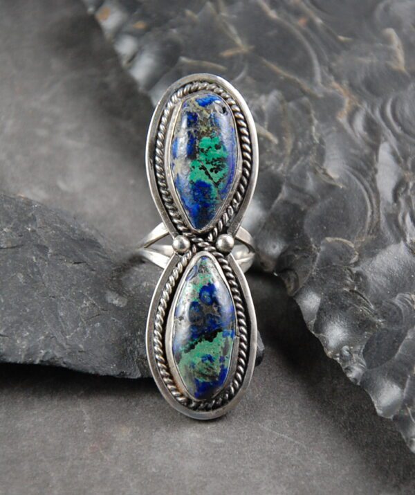A silver ring with two blue and green stones.