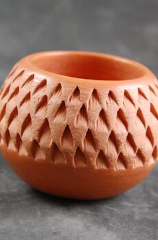 A small clay vase with a pattern on it.