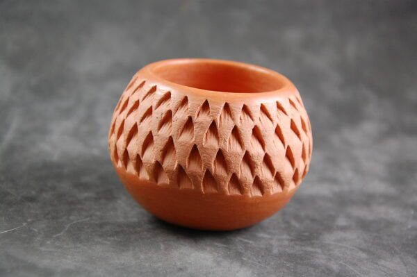 A small clay vase with a pattern on it.