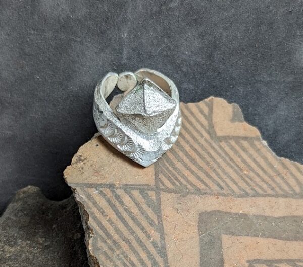 A silver ring sitting on top of a piece of cardboard.