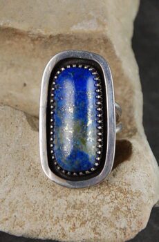 A silver ring with a blue stone on top of it.