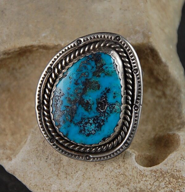 A turquoise ring is shown on top of a rock.