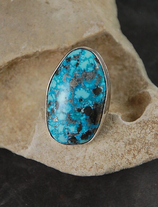 A turquoise ring is shown on top of a rock.
