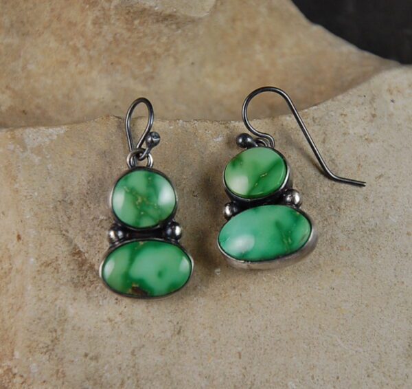 A pair of green earrings sitting on top of a rock.
