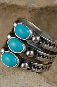 A silver ring with three turquoise stones on it.
