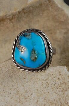 A turquoise ring is shown on top of a stone.