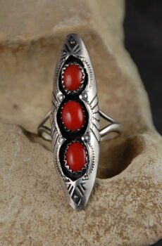 A silver ring with three red stones on it.