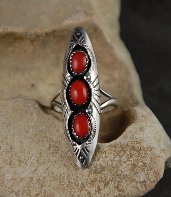 A silver ring with three red stones on it.