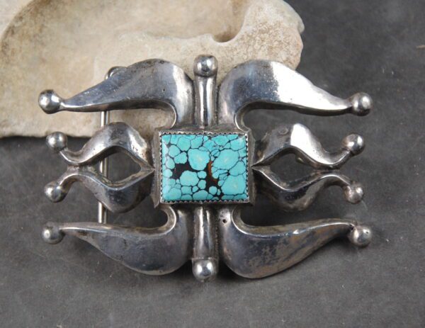 A silver brooch with turquoise stone on it.
