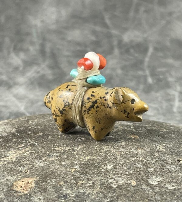 A bear figurine with a colorful bead on its back.