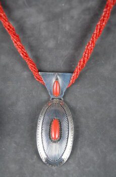A silver and red necklace with a large pendant.