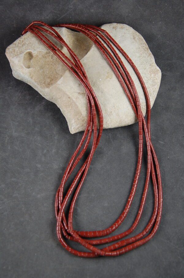 A red string necklace is laying on top of a rock.