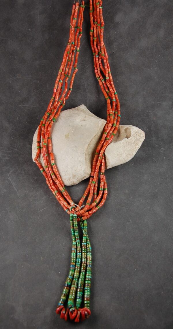 A necklace of orange and green beads is hanging on the rock.