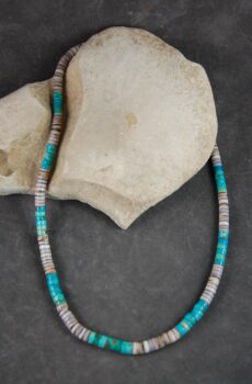 A necklace of turquoise and shell beads on a stone
