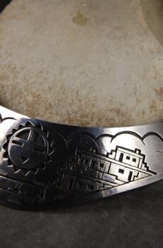 A silver bracelet with a picture of a building.