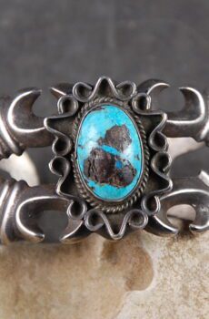A silver bracelet with turquoise on top of it.