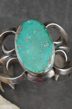 A silver bracelet with a turquoise stone on it.