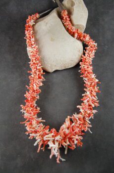 A coral necklace is laying on the ground.