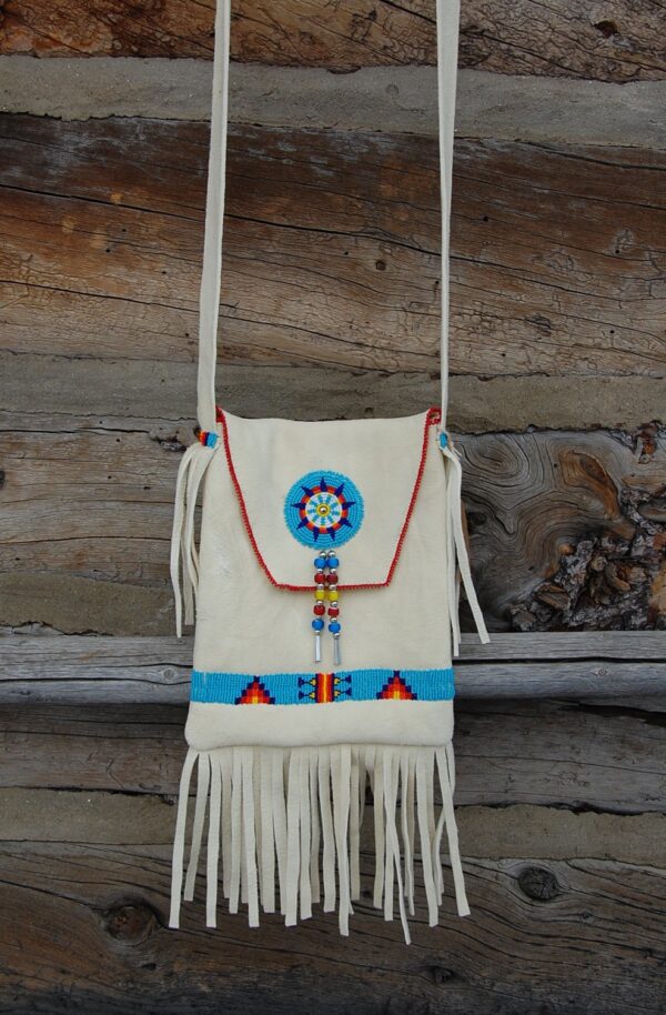 A bag with a fringed bottom and a beaded decoration.