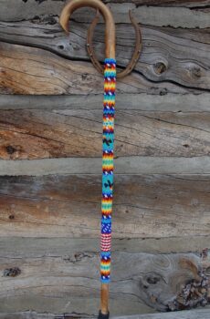 A wooden wall with a colorful bead necklace hanging on it.