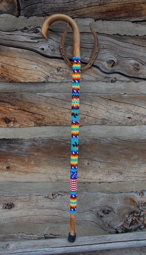 A wooden wall with a colorful bead necklace hanging on it.