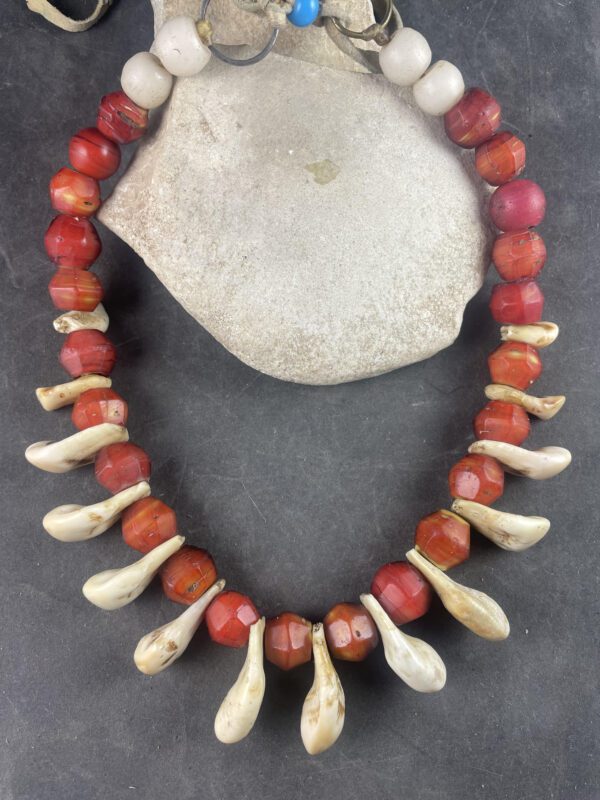 A necklace of red and white beads on a gray surface.