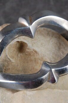 A silver heart shaped ring sitting on top of a box.