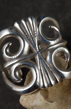 A silver ring with swirls on it's side.